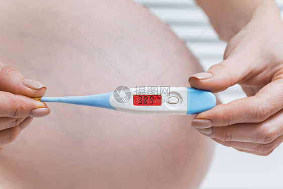 有电子温度计的孕妇高温怀孕期图片