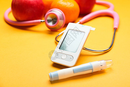 彩色背景下的数字血糖仪柳叶刀笔听诊器和水果糖尿病概念背景图片