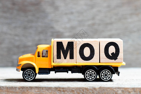 卡车在木材背景上持有MOQ字形的字母块简化最图片