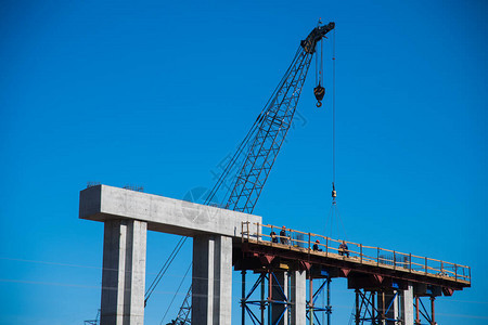 建设跨河公路桥交汇处建筑工地上的建筑工人和建筑设备对蓝天图片