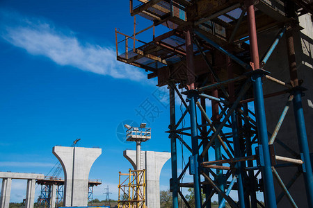 建设跨河公路桥交汇处建筑工地上的建筑工人和建筑设备对蓝天图片