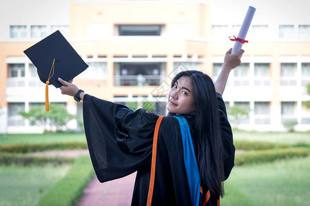 年轻的亚洲女大学毕业生穿着毕业礼服和帽子图片