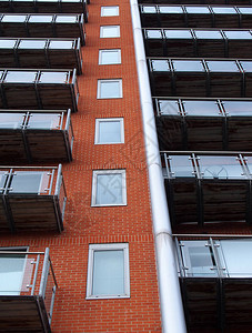 向上看现代公寓楼砖墙和玻璃阳台有窗户的图片