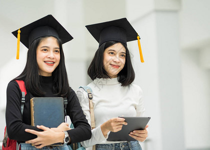 对持有背包书和戴毕业帽子的女青少年大学生的肖像代表了毕业概念教育版照片校对背景图片