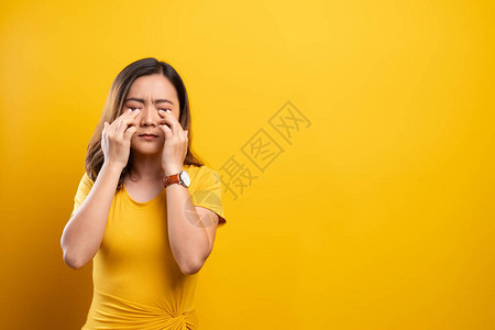 女人的眼睛疼痛被黄色背景隔离图片