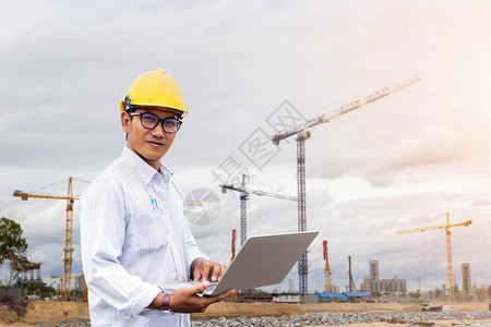 亚洲工程师用笔记本电脑和建筑背景在工地施图片