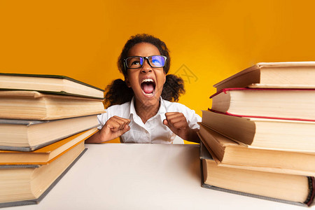 愤怒的非裔美国女孩在书堆间学校在家做务时喊叫图片