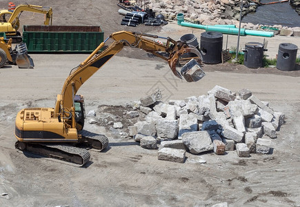 工业挖掘机在施工现场抓取花岗岩块图片