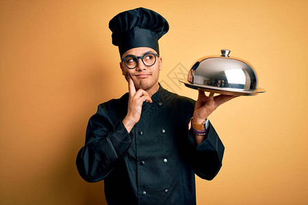 巴西年轻厨师穿着炊具制服和帽子拿着托盘图片