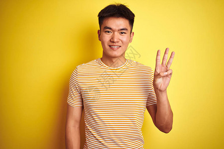 年轻的亚洲华裔男子穿着T恤站在孤立的黄色背景上图片