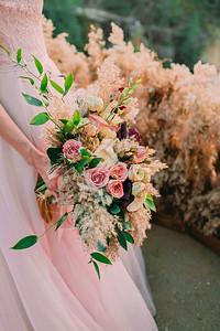 新娘持有由不同花朵组成的生锈的婚礼花束图片