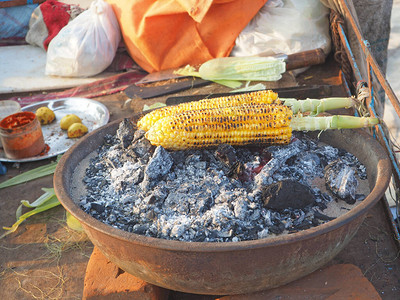 黄色大玉米甜玉米加香料放在热煤上侧观关闭美味背景