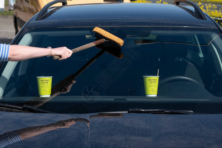 女人用海绵和水清洗汽车的前玻璃图片