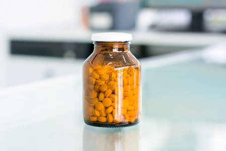 药房桌上琥珀药瓶中的小药丸图片