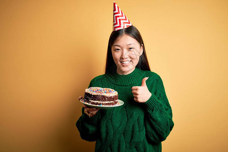 年轻的亚洲女拿着生日蛋糕图片