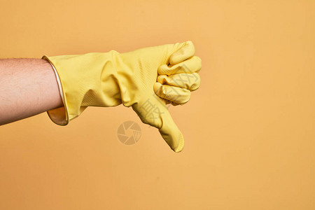 在孤立的黄色背景上用拇指打倒拒绝不赞成和否定的手势图片