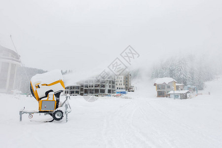 滑雪场上的移动式造雪机抽出雪背景是由于机器喷出而几乎看不到的图片