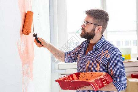 男用油漆滚筒粉刷墙壁一个有趣的家伙在她的新公寓里画墙的肖像重新装图片