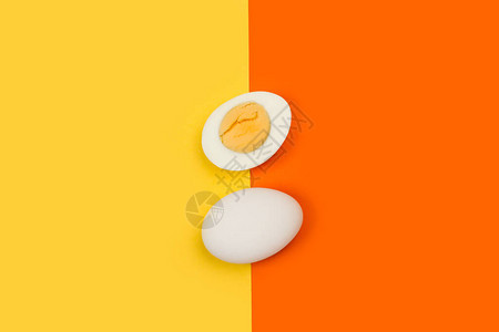 黄色和橙色背景上的半煮鸡蛋和一个鸡蛋图片