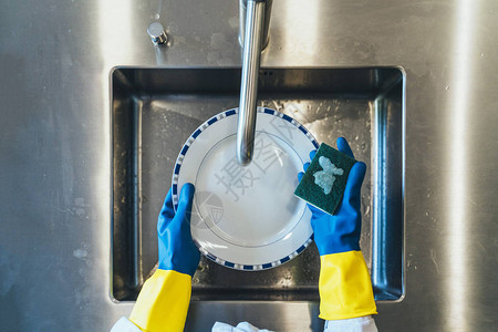 戴手套洗碗的年轻女子图片