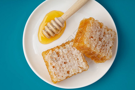 蜂蜜背景梳子里的甜蜂蜜蜂窝和蜂蜜勺蜂蜜在一个白色的陶图片