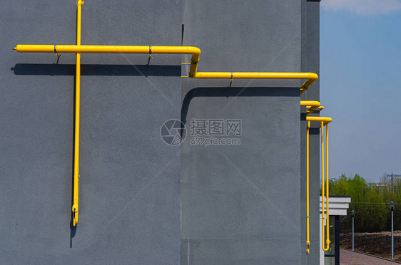 多层建筑立面上带通风口的黄色燃气管图片