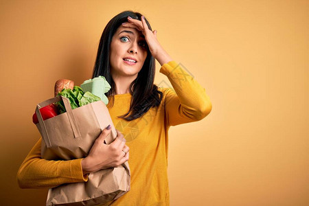 蓝眼睛的黑发年轻女人用超市纸袋装着健康食品图片