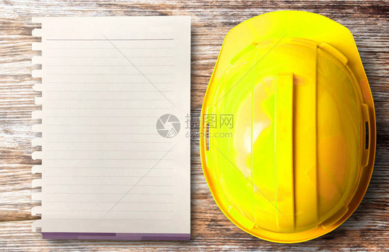 在木桌背景的建筑工地项目中黄色安全帽和白纸的顶部视图图片