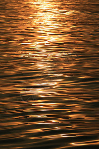 金色晨光闪亮的金色阳光照耀着温柔的波纹在海图片