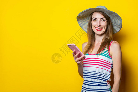 戴着帽子和条纹衣服的快乐微笑的年轻女子拿着电话图片