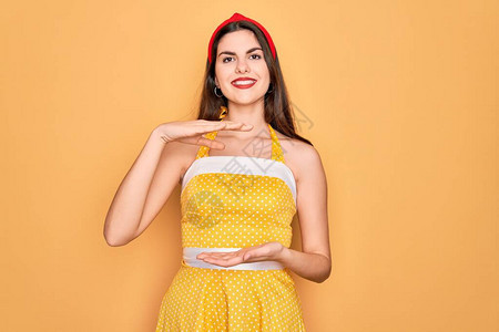 年轻漂亮的女人穿着50年代时尚复古连衣裙在黄色背景上图片