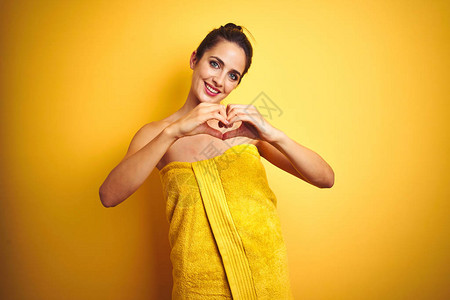 年轻美女在黄色孤立的背景下洗完澡后穿着毛巾图片