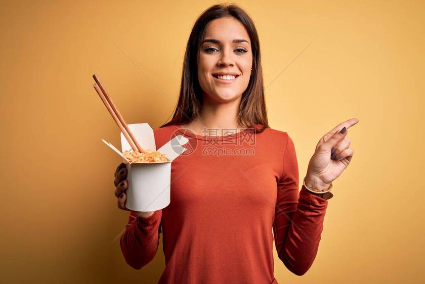 用筷子吃外卖面条的褐发美女非常高兴地用手和图片