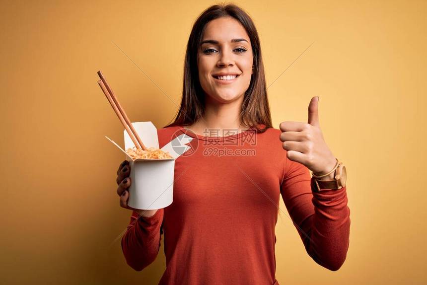 年轻漂亮的褐发女人用筷子吃外卖面条图片