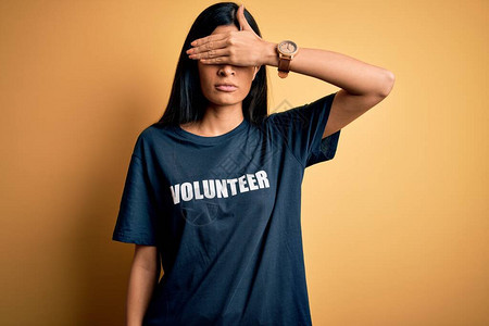 年轻漂亮的西班牙裔女穿着志愿者T恤作为社会慈善道德图片