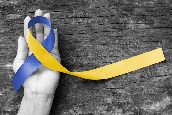 为3月21日世界唐氏综合症日WDSD伸出援手的蓝黄色意识丝带提高了对患有唐氏综合症疾病残疾和胸廓出口综合症的患者的支持图片