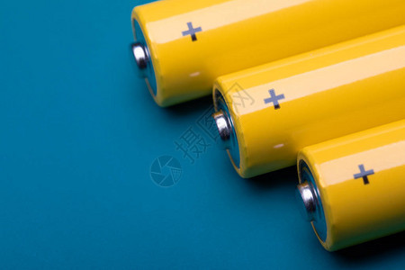 近距离拍摄黄色AA碱电池或浅聚焦蓝底可充电的图片