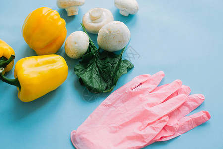 在隔离区安全购物与蔬菜在蓝色背景上的粉红色手套通过送货在线订购食物并留在家中预防流图片