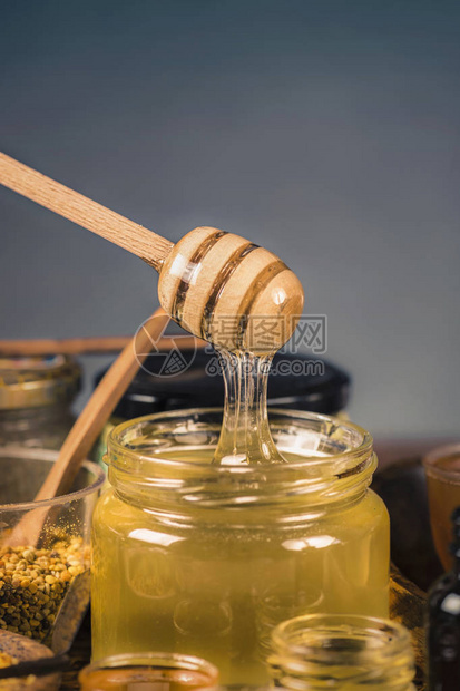 蜂蜜流入玻璃罐的木制北斗各种类型的蜂蜜蜂花粉蜂胶和木制蜂图片
