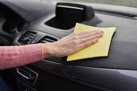 妇女手用黄色微毛巾清洁汽车仪表板和黄色图片