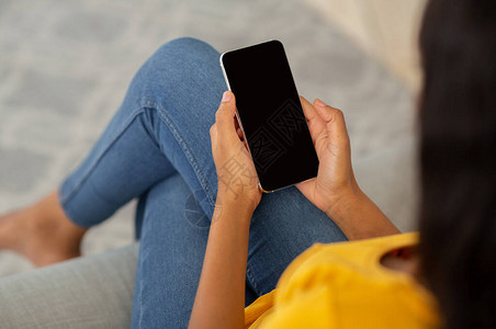 千禧一代黑人女士使用带空屏幕的智能手机在家中在线工作或的特写视图图片