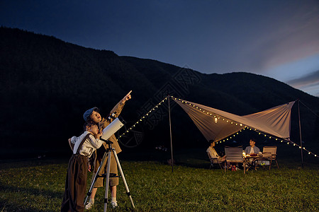 夜晚帐篷儿童露营夜晚使用天文望远镜看星空背景