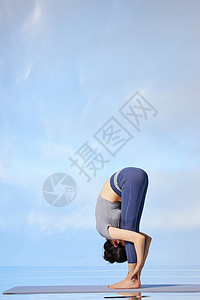 蓝色天空背景下做瑜伽运动的女性图片