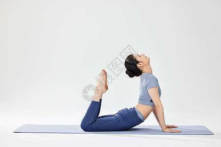 在瑜伽垫上做瑜伽运动的女青年图片