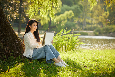 女生在户外画画在公园树下画画的美女背景