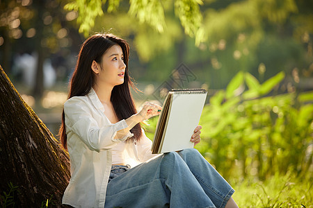 女生在户外画画在公园树下画画的女性背景