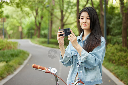 美女骑行使用手机拍照图片