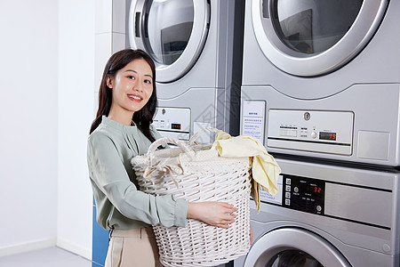 用洗衣机洗衣服的青年女性背景图片