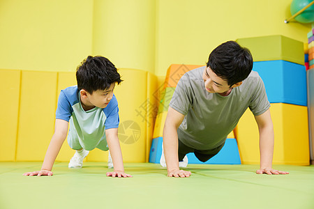 儿童体能素质教练带着男孩一起做俯卧撑背景