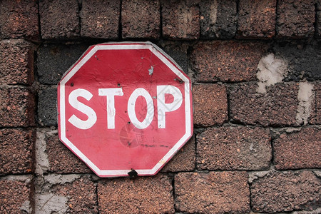 红墙上的旧无用交通标志STOP背景图片